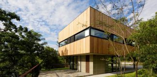 Rectangular house opens wide towards the lake surface and surrounded by rich greenery