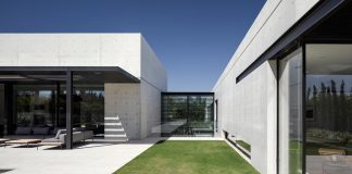 Minimalist concrete and glass house consists of two volumes connected by an glazed corridor