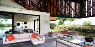 Exposed concrete for the first floor and a second floor covered in Corten steel panels with different size perforations