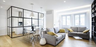 Kitchen is separated through a glazed system divided by a regular square mesh grille and with a very industrial aspect