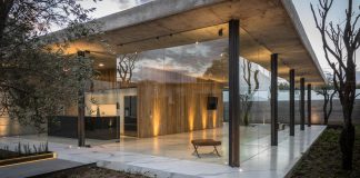 House which manifests its character with an apparent concrete wall and with wooden access doors